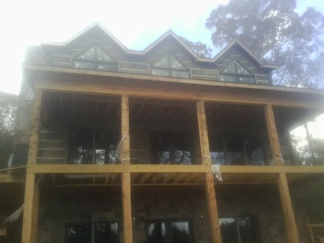 Dormers and porch framing on a large log home under construction — Roof Coating work by our crew in Winnsboro