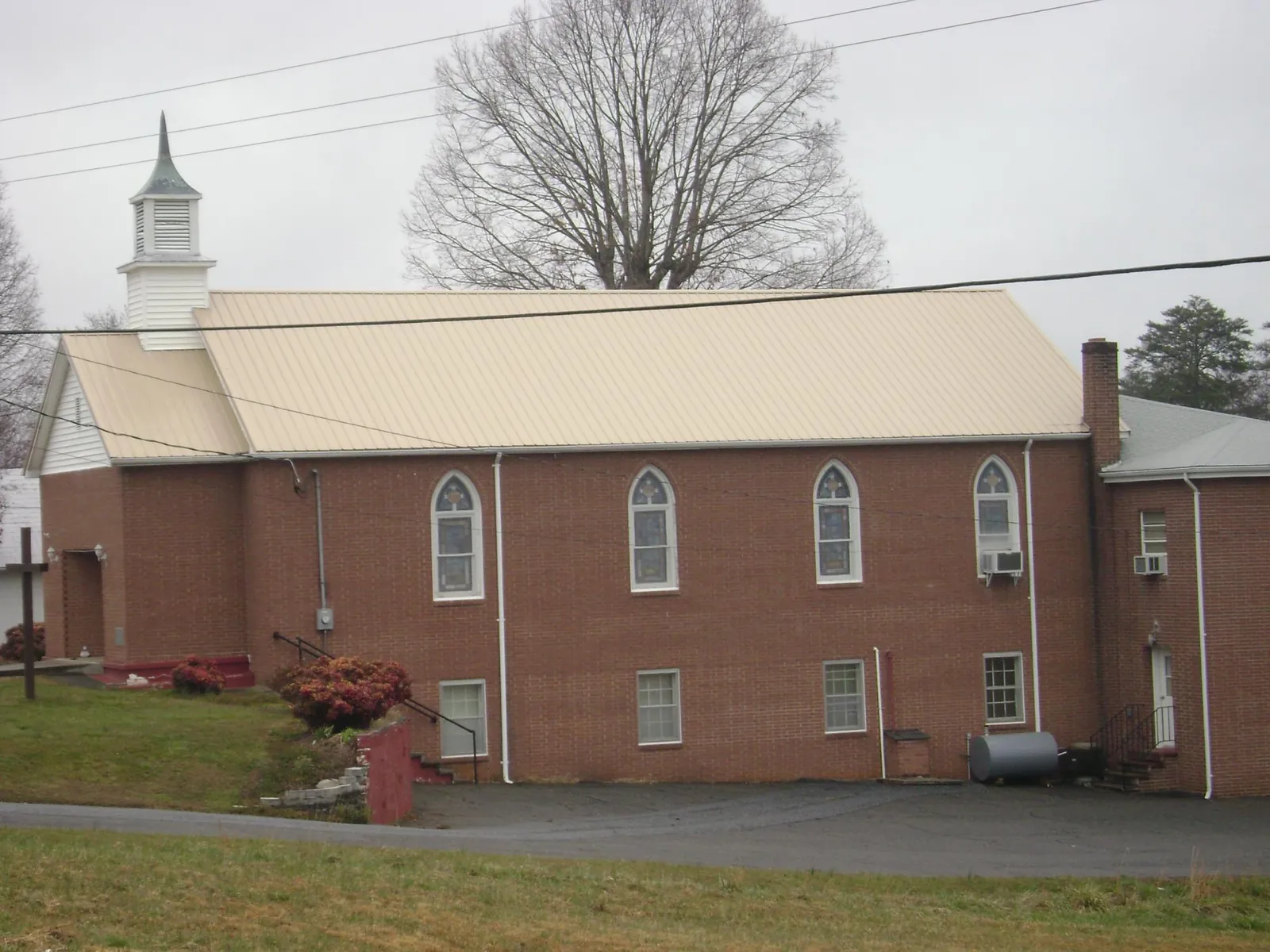 New tan metal roof on a brick church with a white steeple in Winnsboro