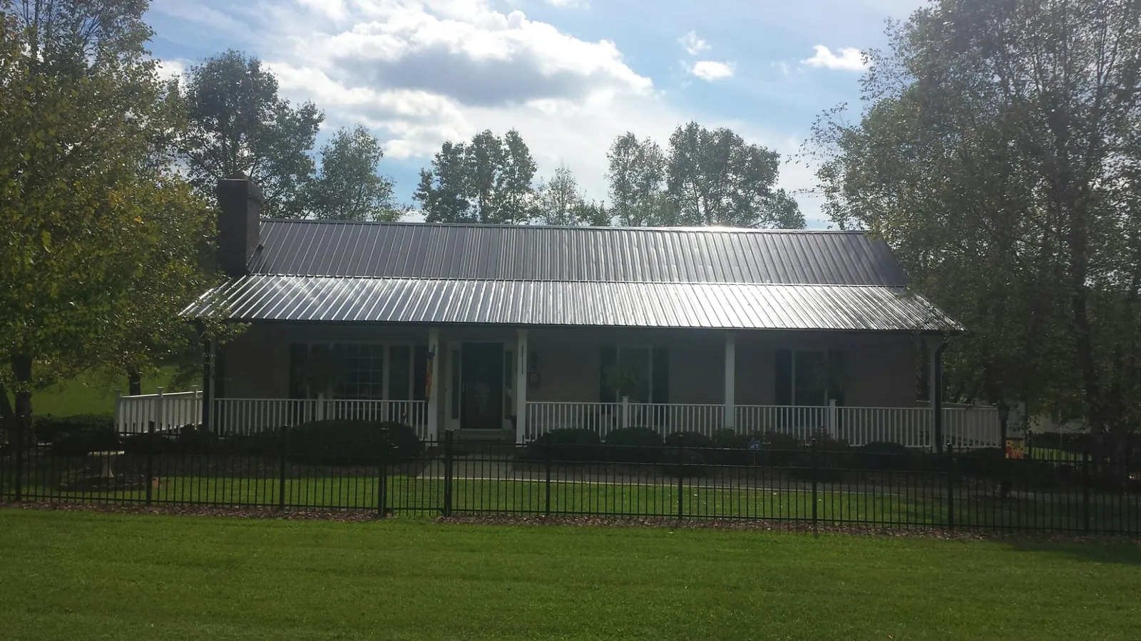 Gray metal roof on a brick ranch with a full width front porch — Gutter Guard Installation work by our crew in Winnsboro