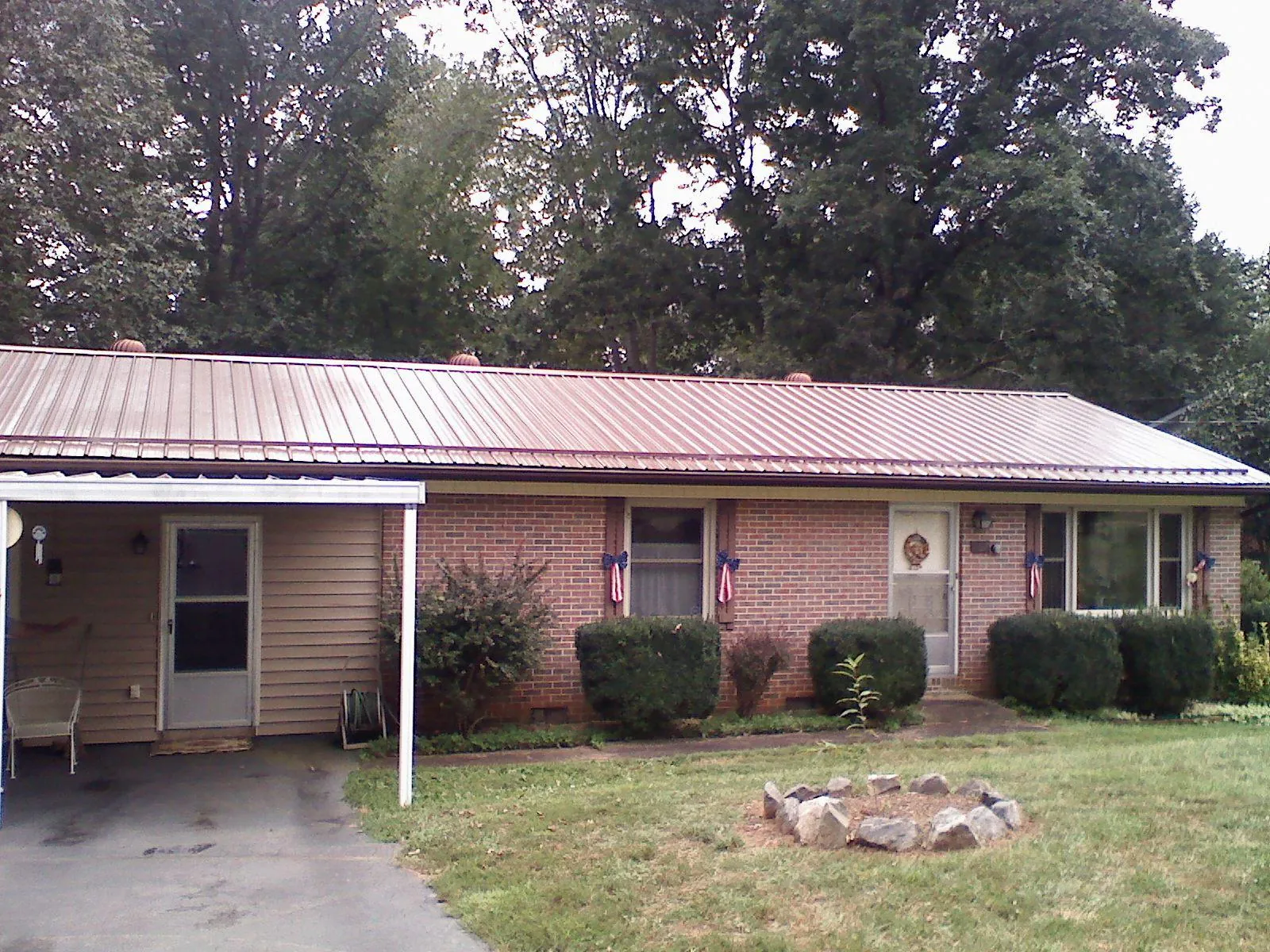 Bronze metal roof and carport on a brick ranch home — Roof Repair work by our crew in Winnsboro