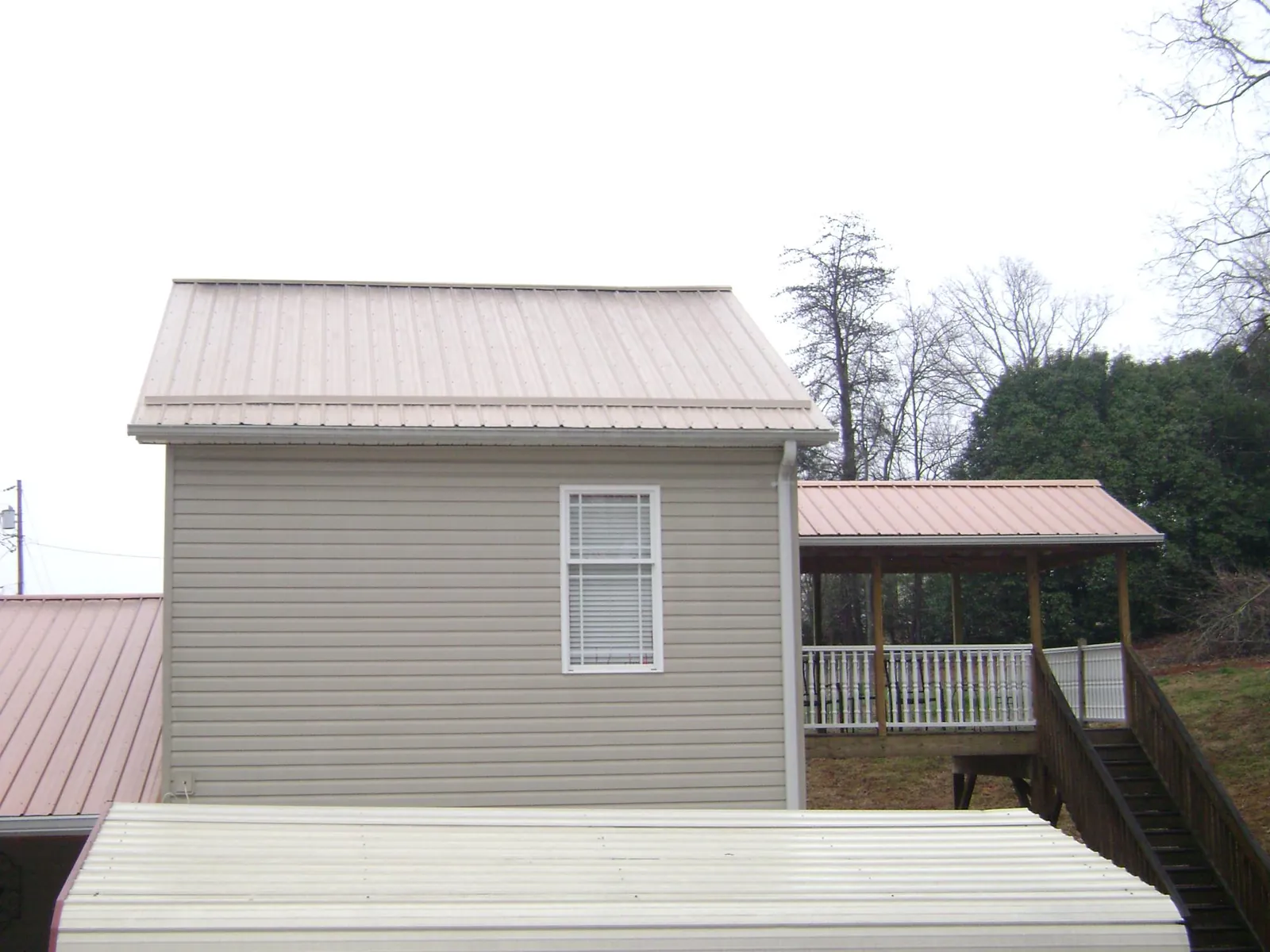 Tan metal roofs on a two story addition and attached porch, from a Roof Replacement job in Winnsboro