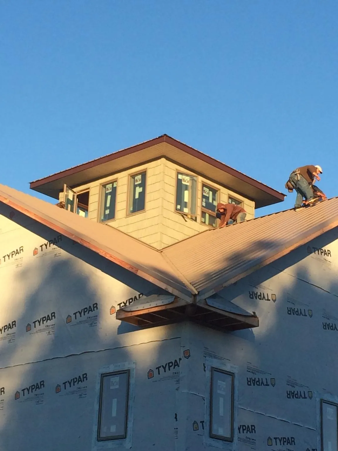 Roofers working around a rooftop cupola on a new metal roof at sunset — Roof Waterproofing in Winnsboro by Roofing Brothers